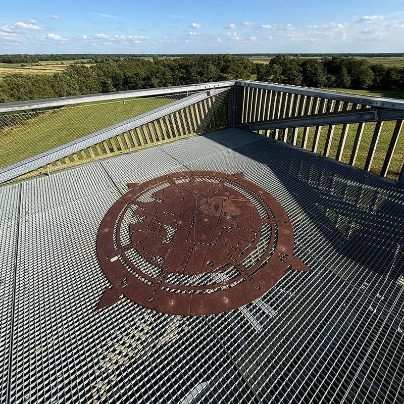 Een metalen kompasroos in de vloer van een uitkijktoren in de Onlanden